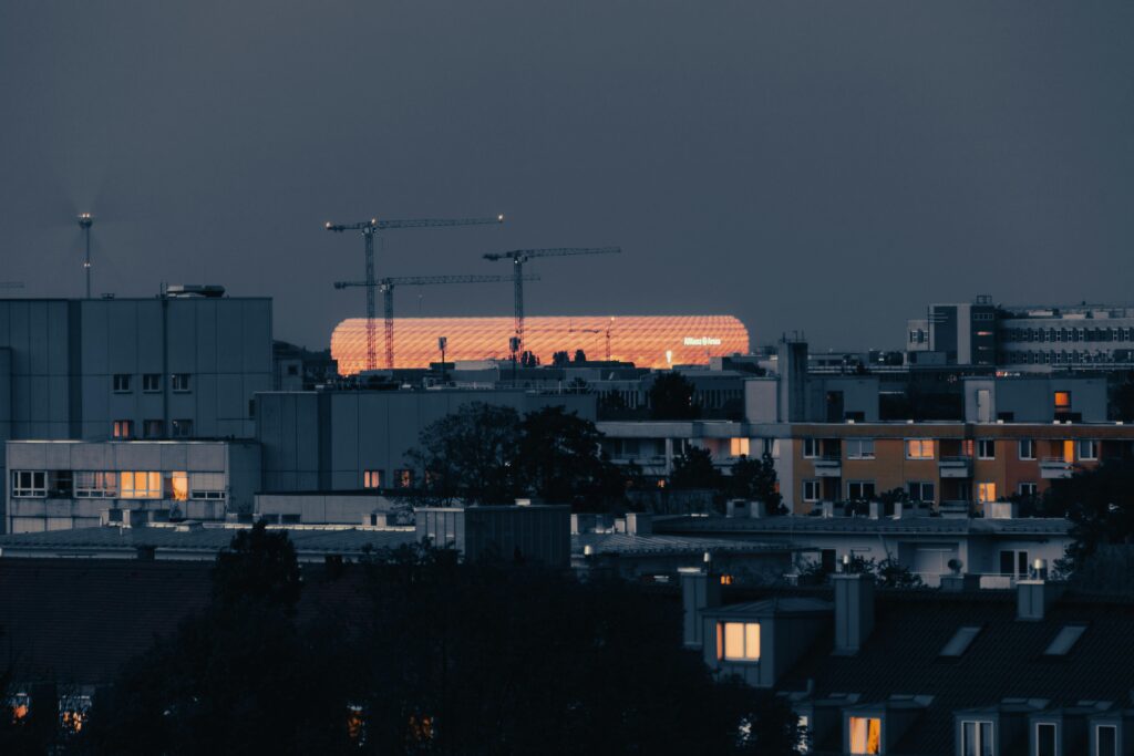 Illuminated Allianz Arena in Munich's urban skyline at night, showcasing modern architecture.